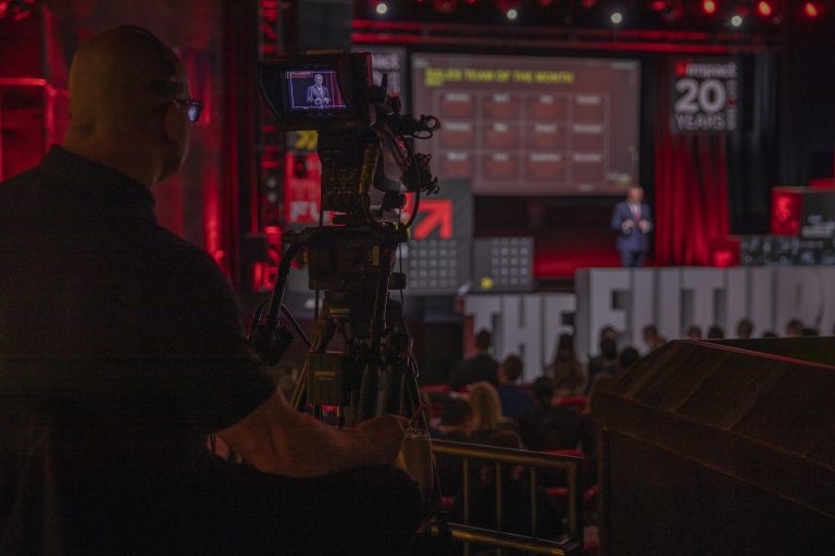 Camera man filming presentation on stage for Impact Networking.