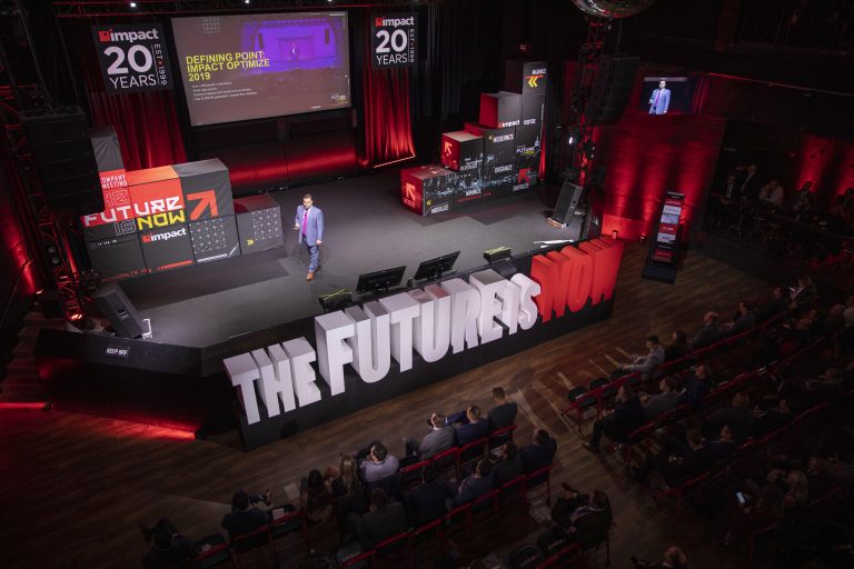 Man presenting on stage at Impact all company event.